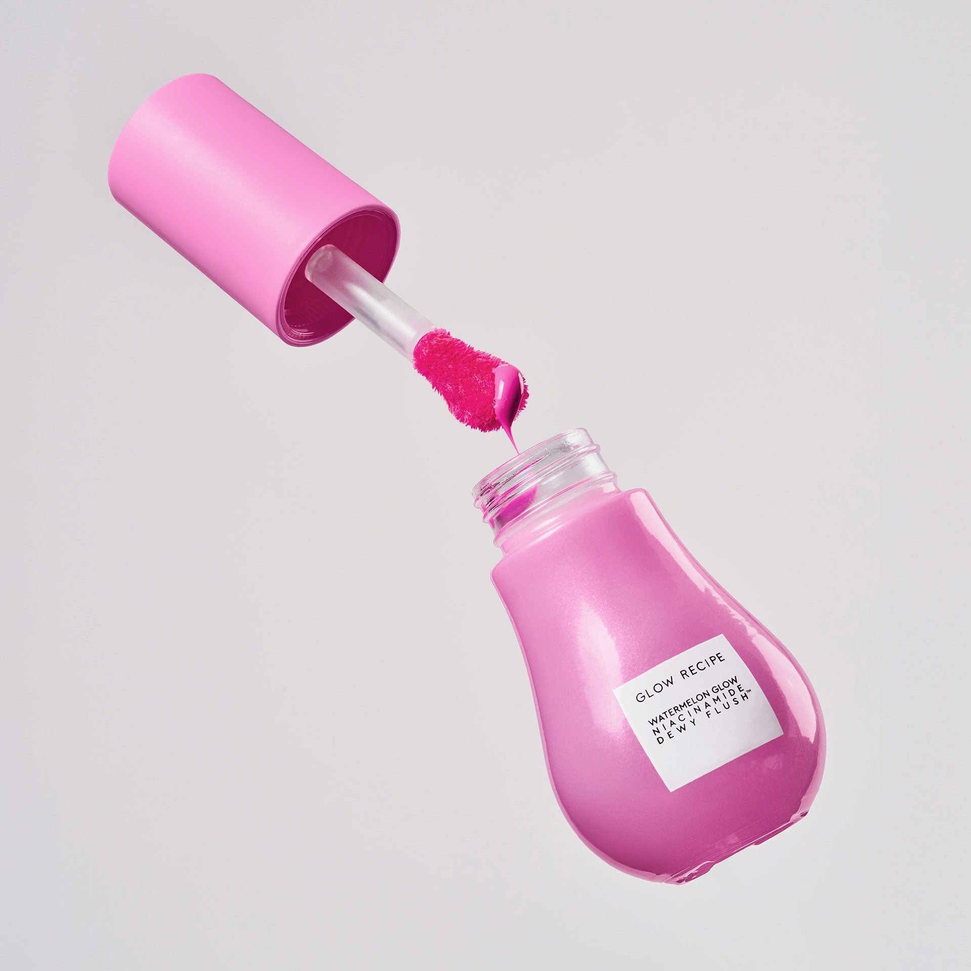 Dragon Fruit Flush Dewy Flush bottle stands upright, showcasing its sheer bright pink tint through clear glass.