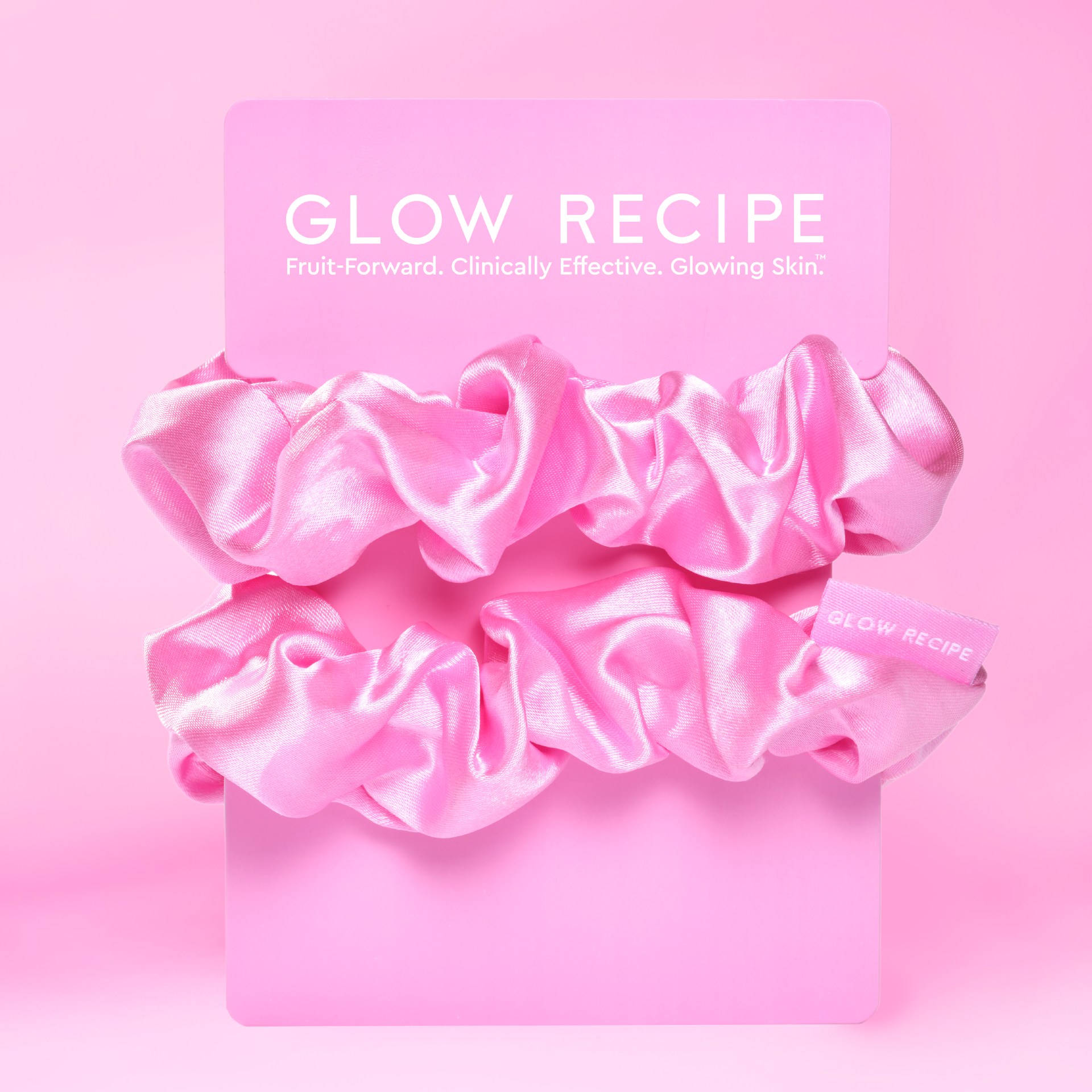 Pink scrunchies with a Glow Recipe band on a pink background