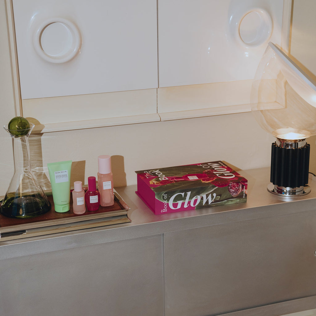 Cosmetic products and a box labeled 'Glow' on a shelf with a neutral background