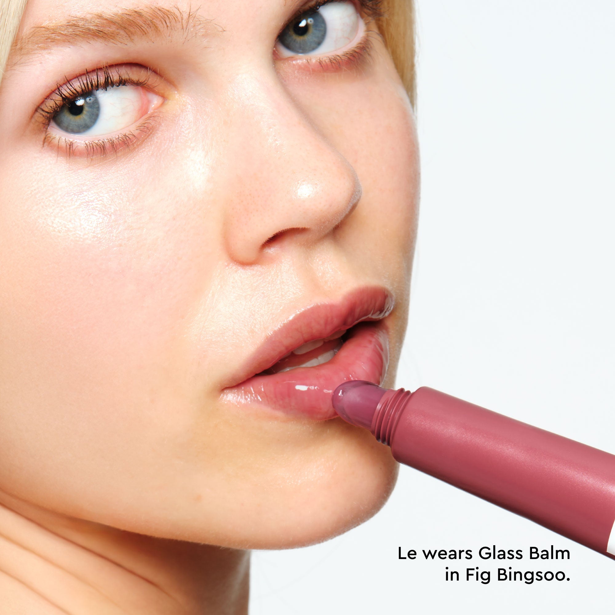Model applying Glass Balm in Fig Bingsoo, showing the sheer mauve-nude tint blended on bare lips.