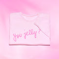 Folded pink sweatshirt with 'you jelly?' text on a pink background