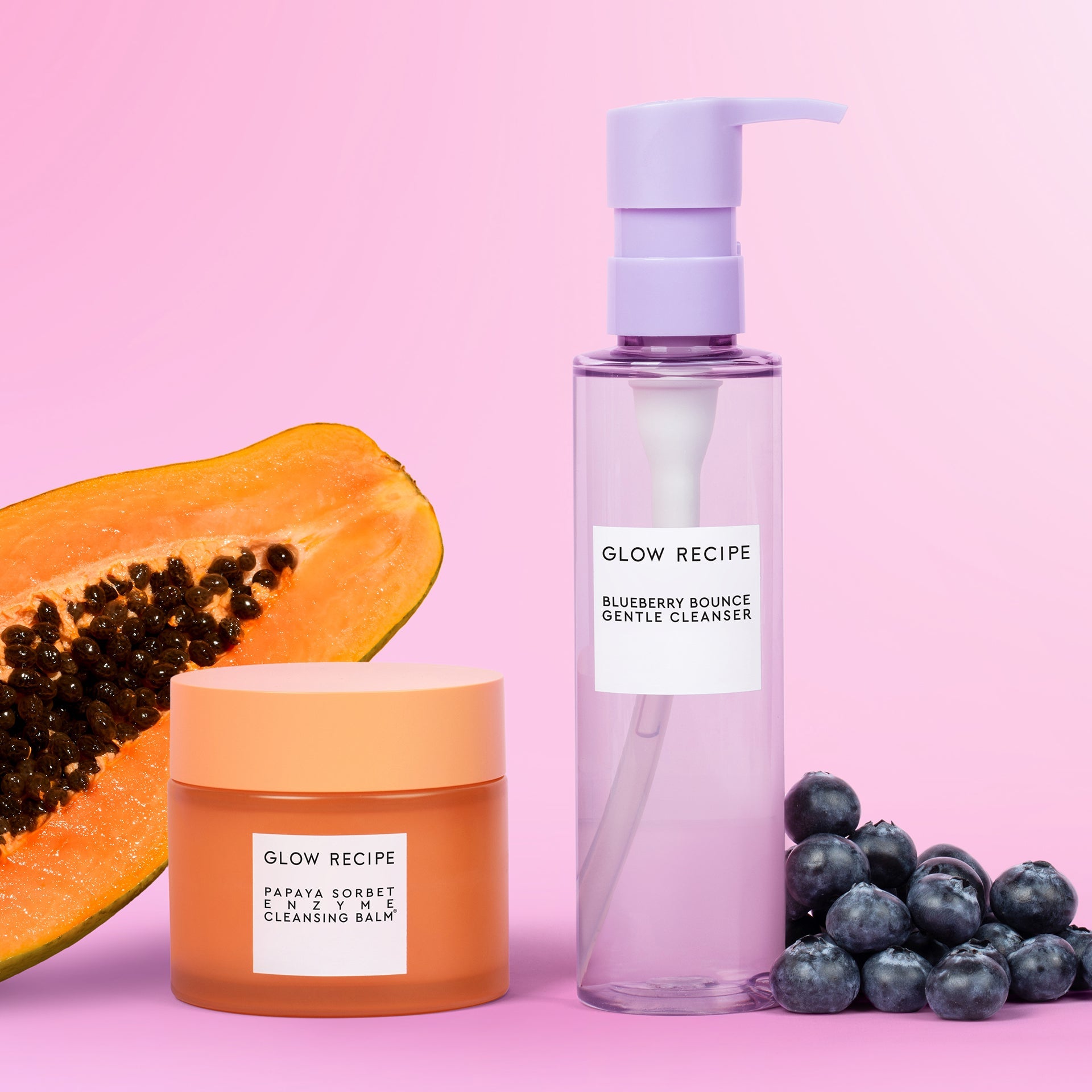 Glow Recipe skincare products including a jar, bottle, and papaya on a pink background