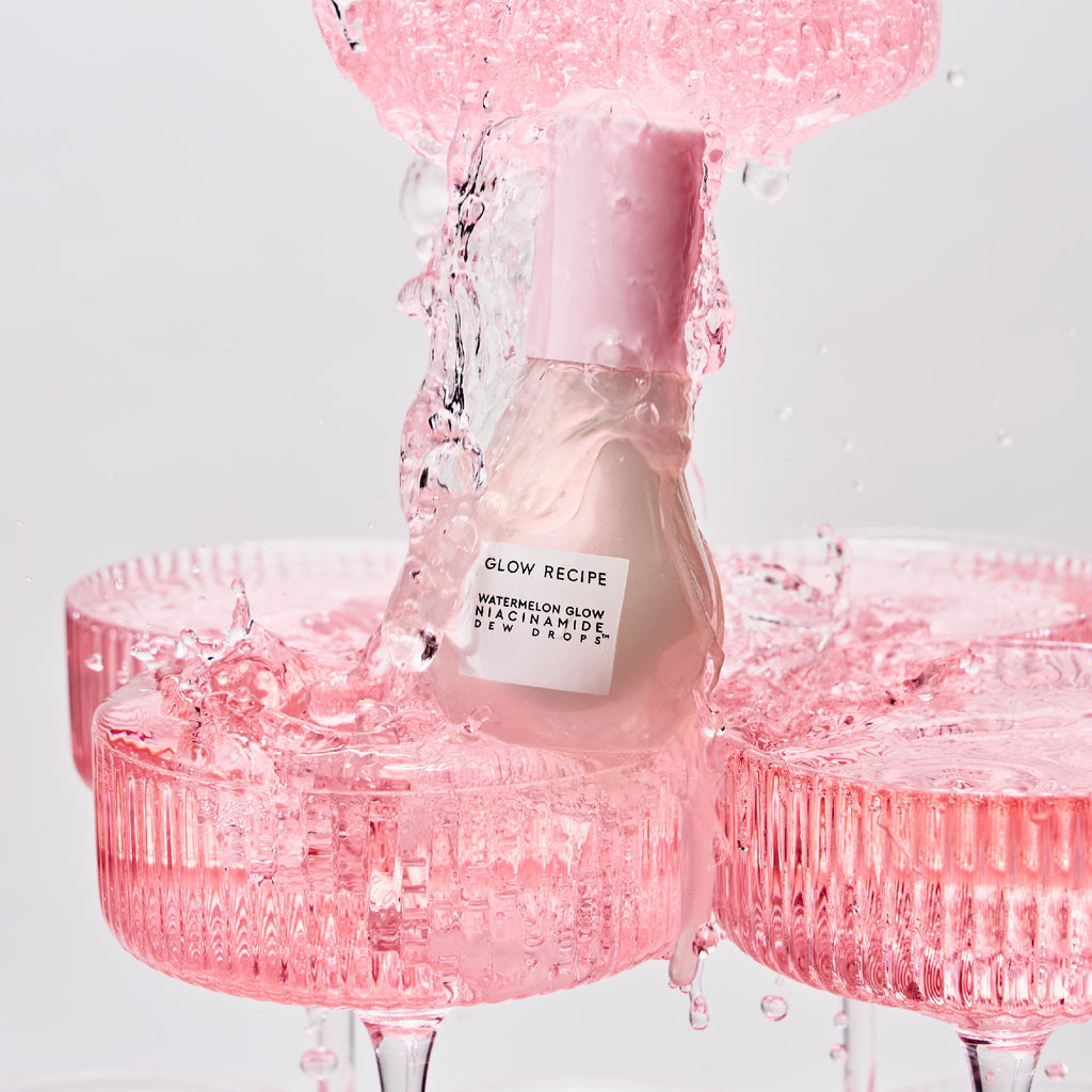 Pink skincare bottle with water droplets on a light gray background