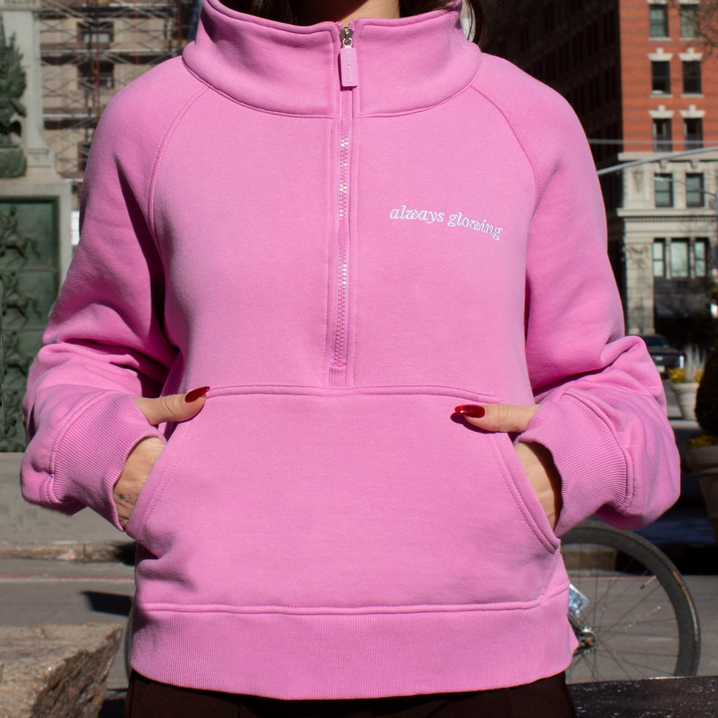 Woman wearing pink zip up. She has her hands in the pouch.