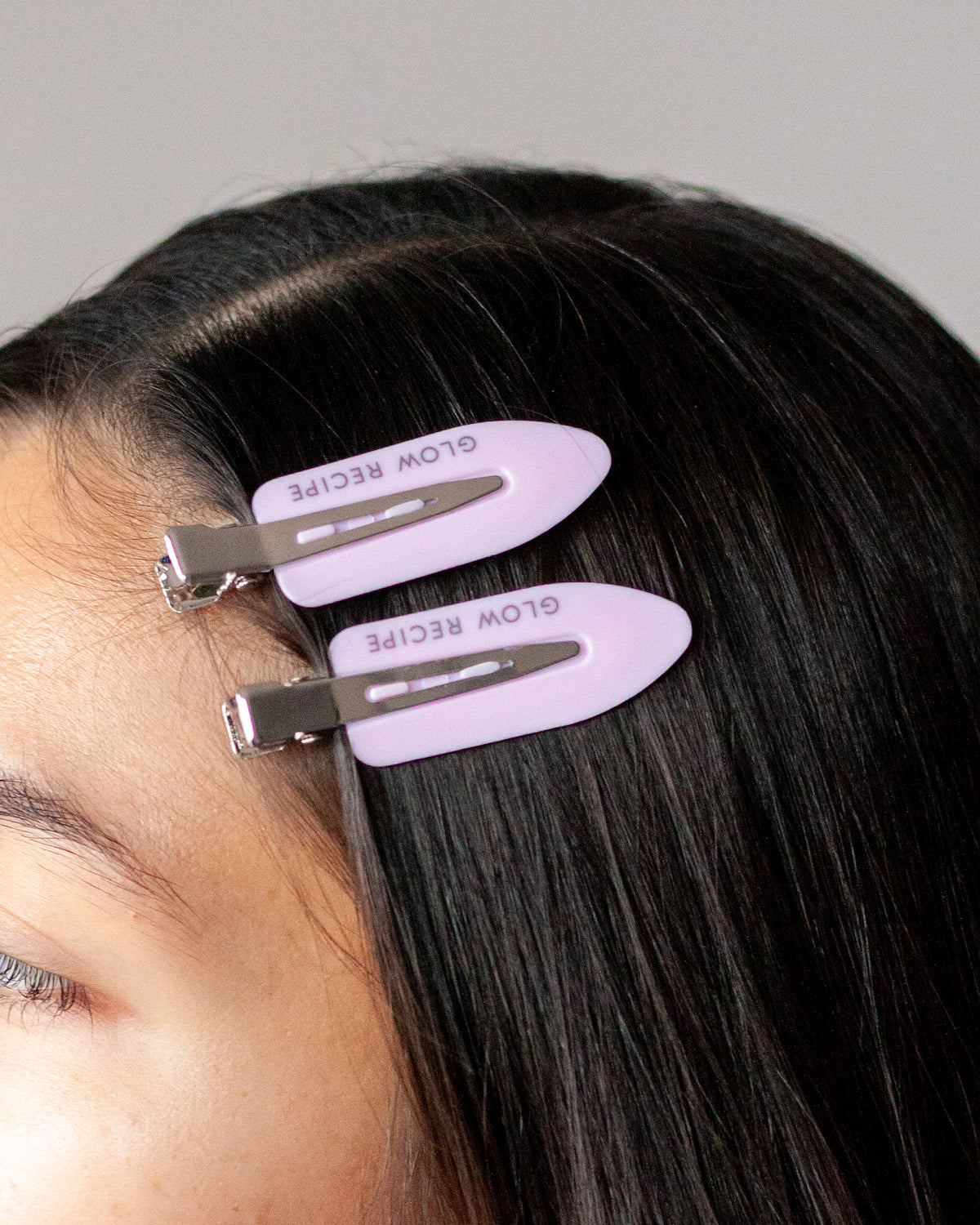 Person wearing pink hair clips with 'Glow Recipe' branding on a gray background