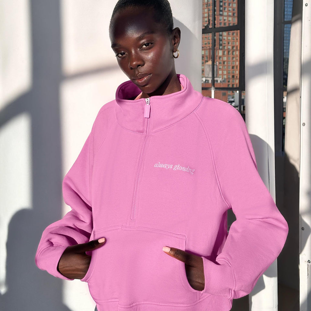 Person wearing a pink hoodie with a brand logo, standing outdoors.