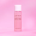 Pink skincare toner bottle with white cap on a pink background