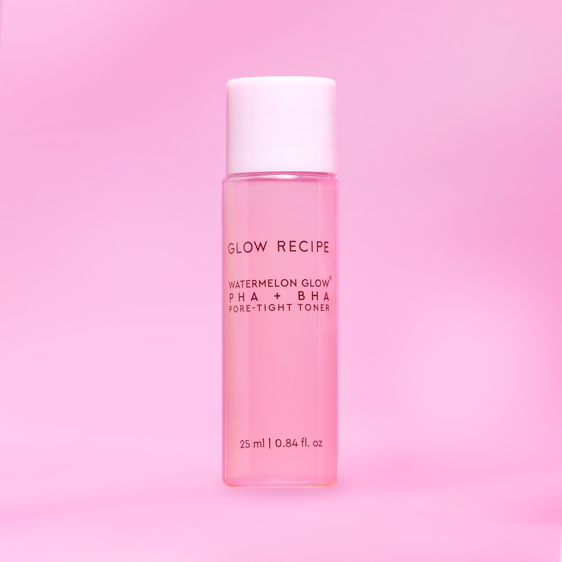 Pink skincare toner bottle with white cap on a pink background
