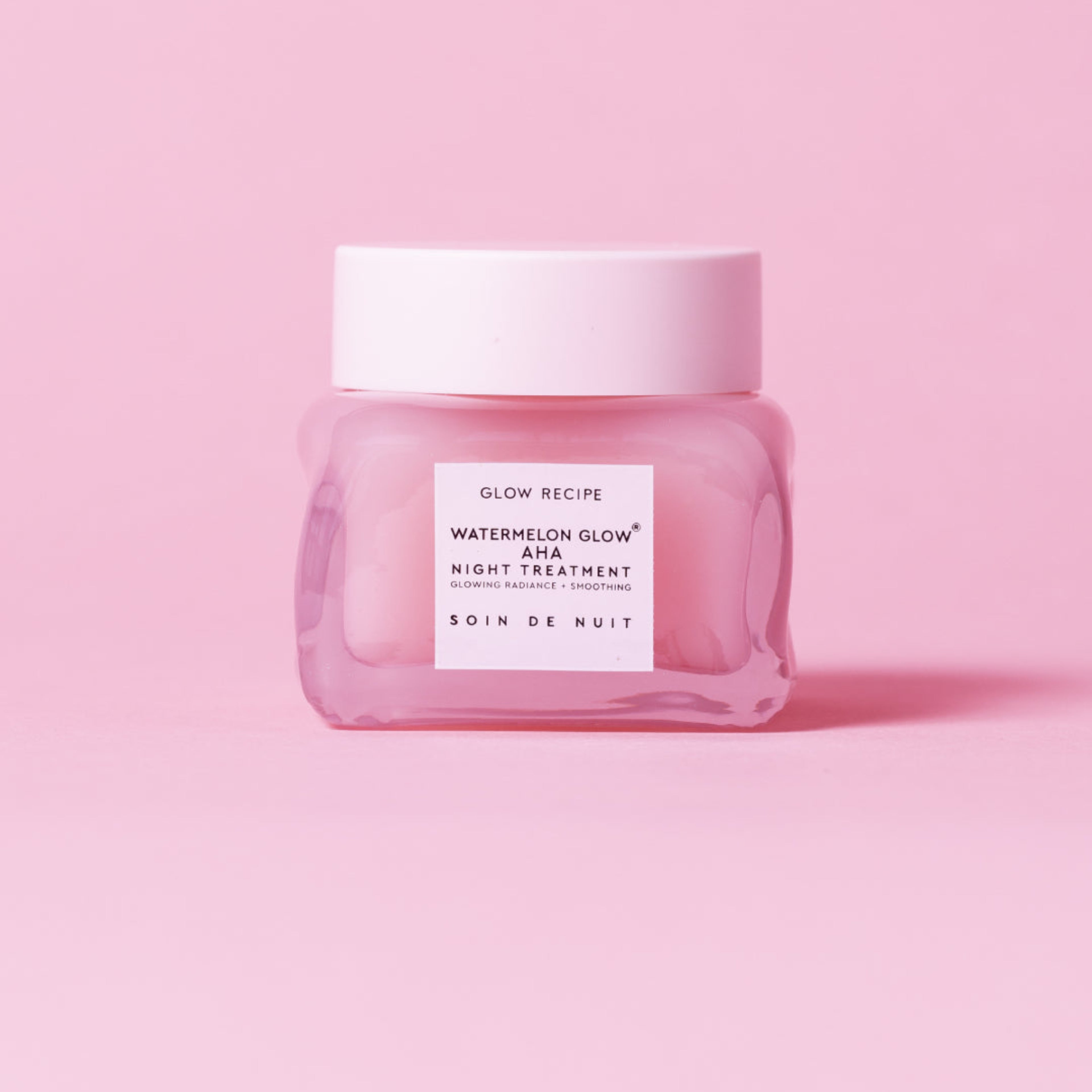 Pink skincare jar with white label on a pink background